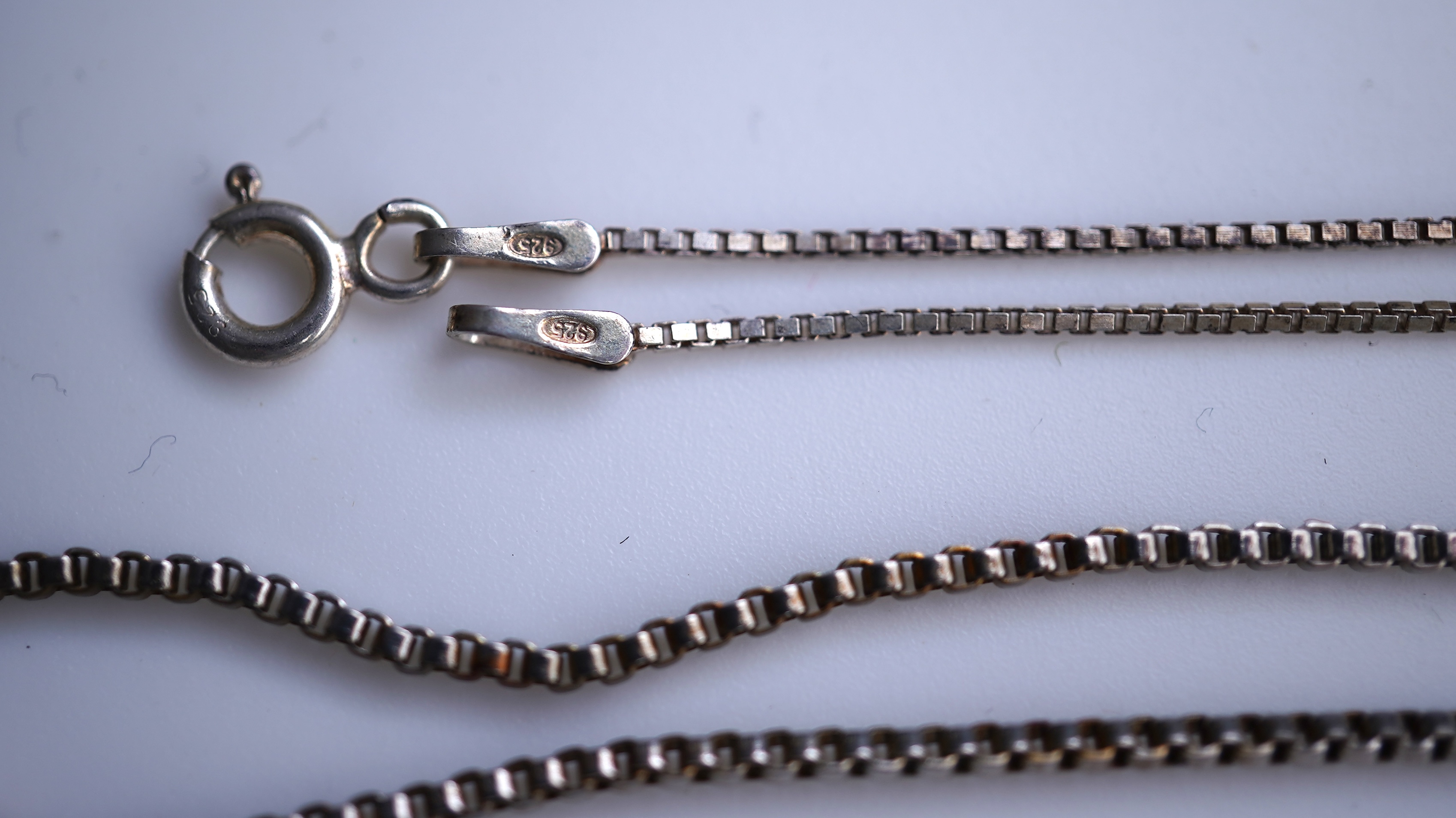 A collection of silver jewels, comprising: a bangle; a chain necklace suspending two winding toothpicks, one with toothpick deficient; a rope twist chain; a pair of cufflinks with the initials DBH; a pendant of abstract